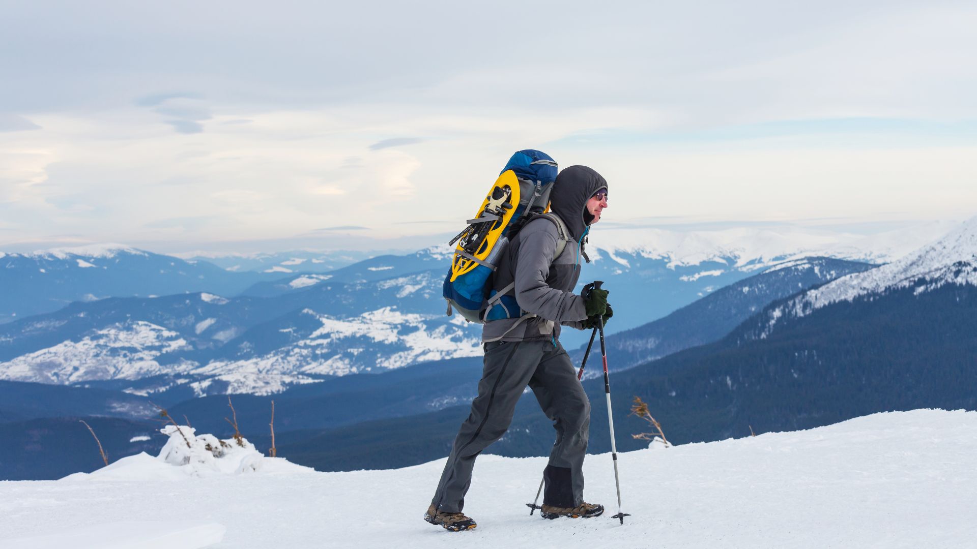 A warmly dressed man embarks on a backpacking trip in the snow