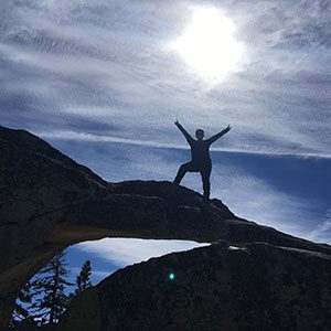 A hiker poses atop their summit in yosemite national park