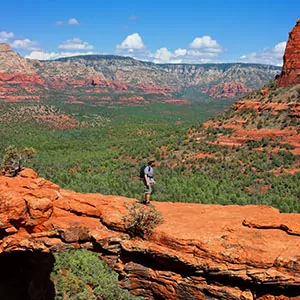 A hiker walks along a sandstone bridge in solitude in Sedona